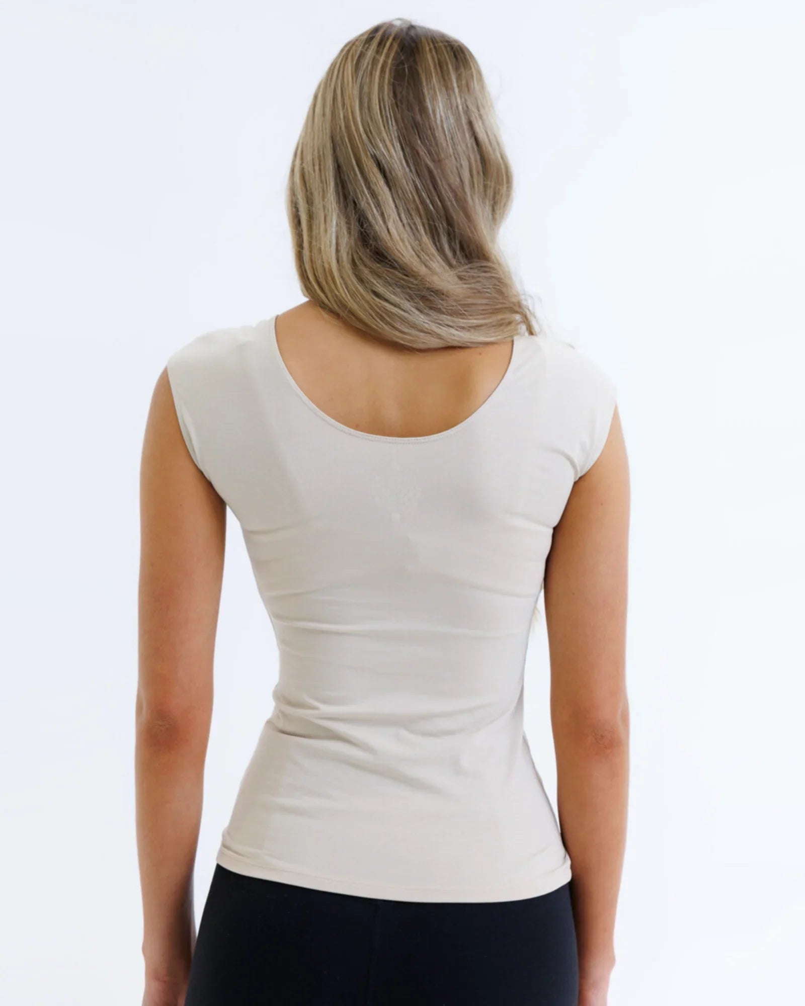 Woman wearing a fitted nude essential tee with cap sleeves, shown from the back